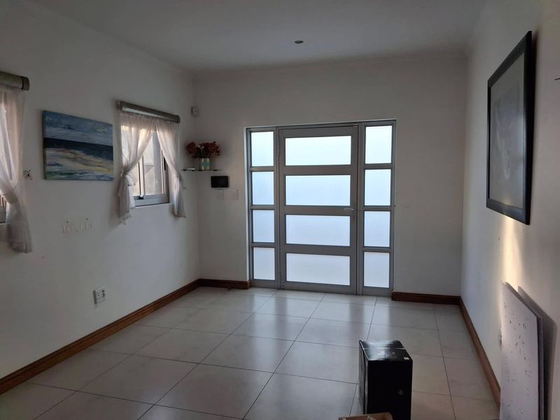 A bright and spacious entrance hall featuring neutral tiled flooring and a modern frosted glass panel front door.