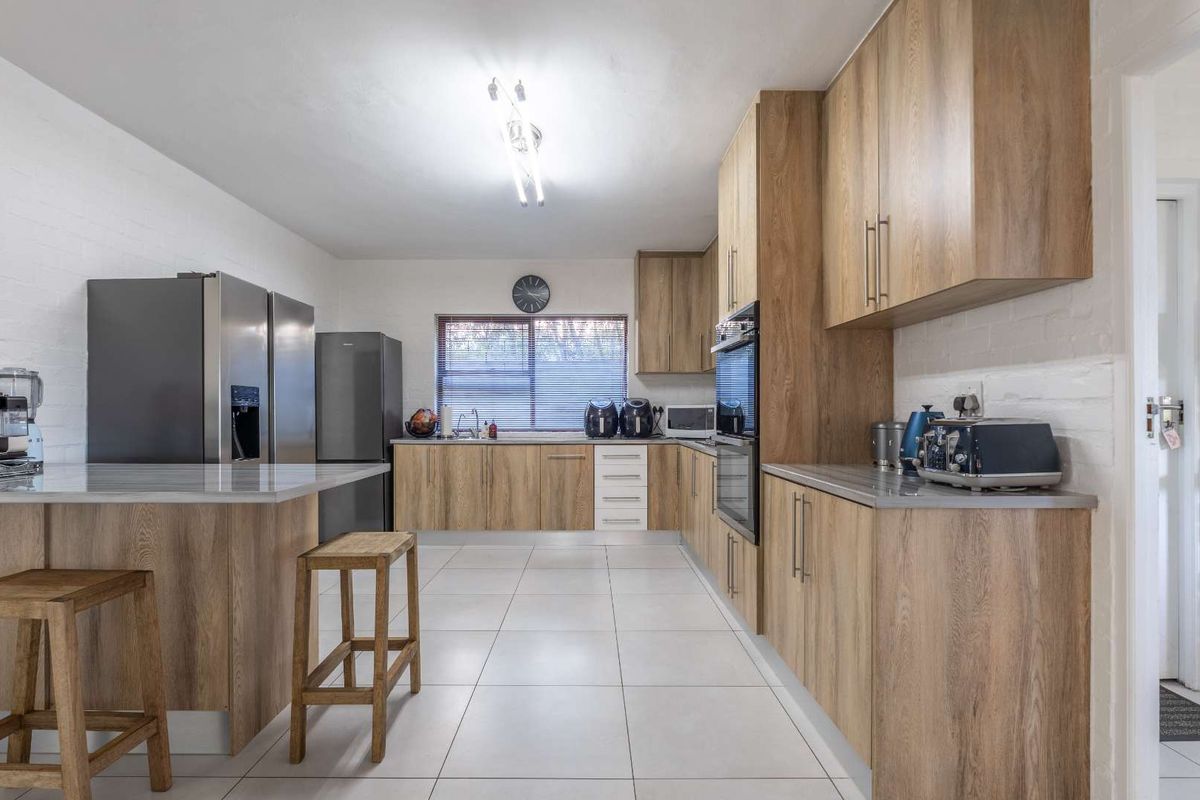 Modern kitchen featuring wood-finish cabinetry, stone countertops, a breakfast bar, and tiled flooring, offering a clean and functional workspace.