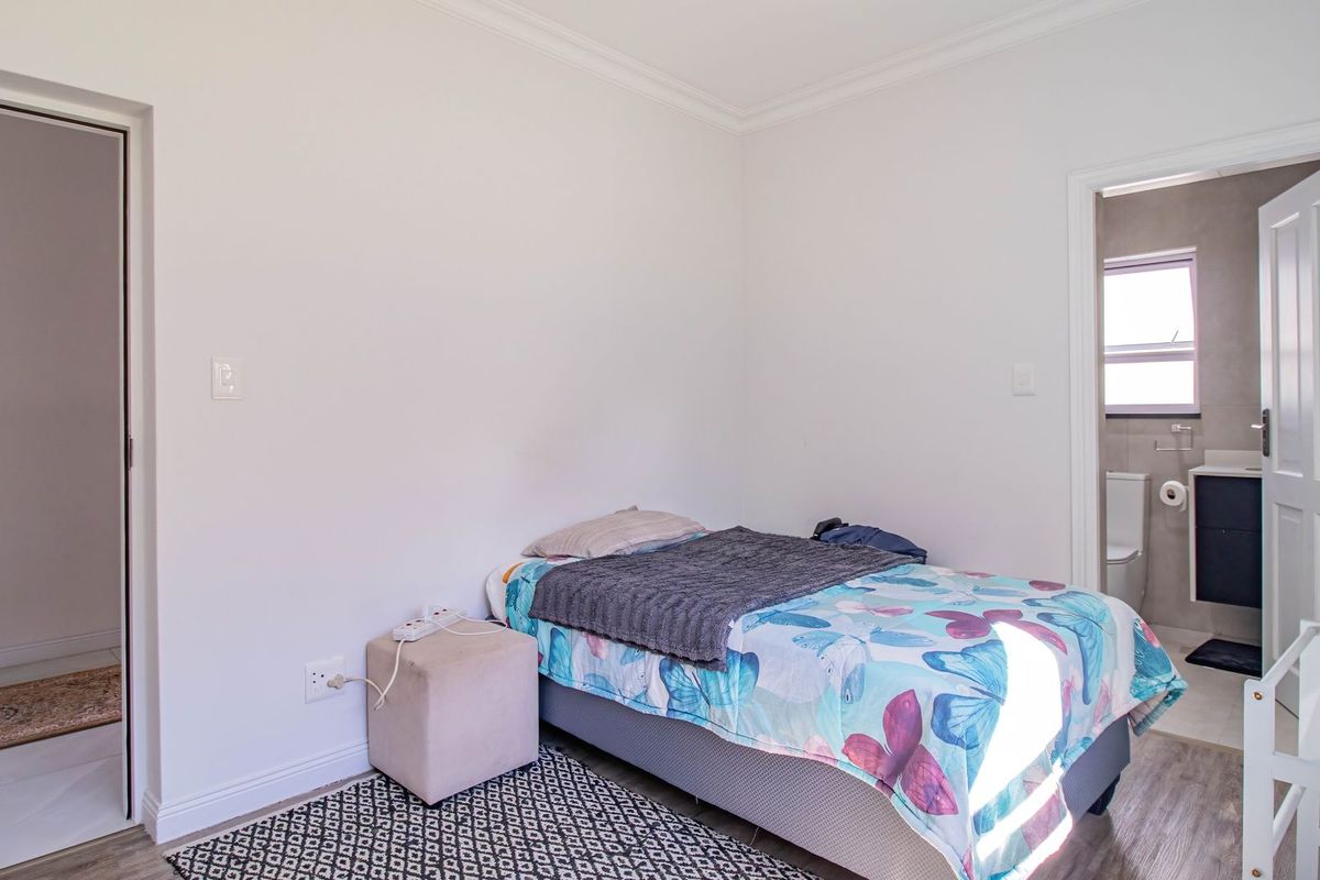 A well-maintained bedroom featuring laminate flooring, neutral walls, and an attached en-suite bathroom, offering a clean and functional living space.