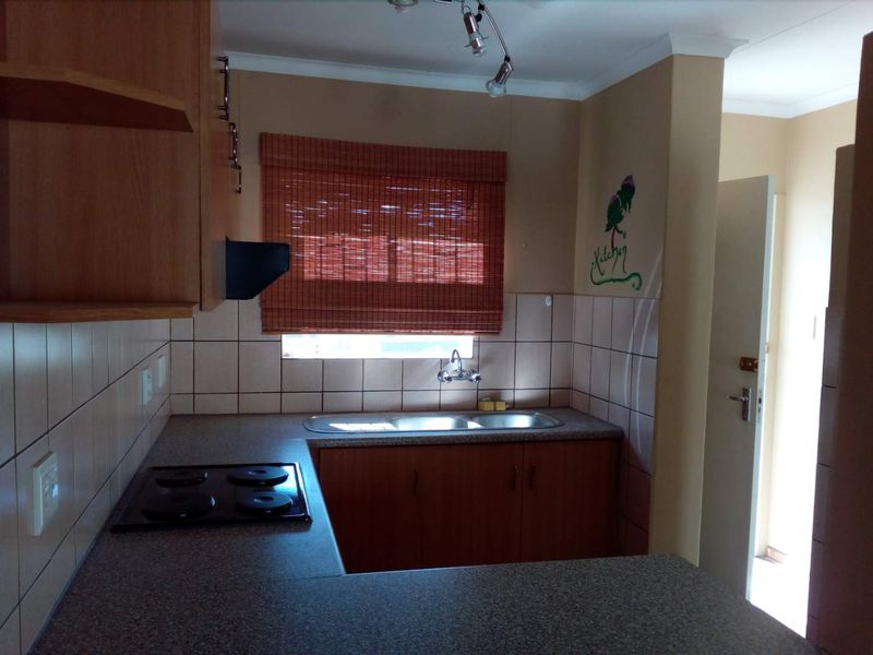 Functional kitchen featuring laminate cabinetry, double bowl stainless steel sink, electric hob, extractor fan, and tiled backsplash.