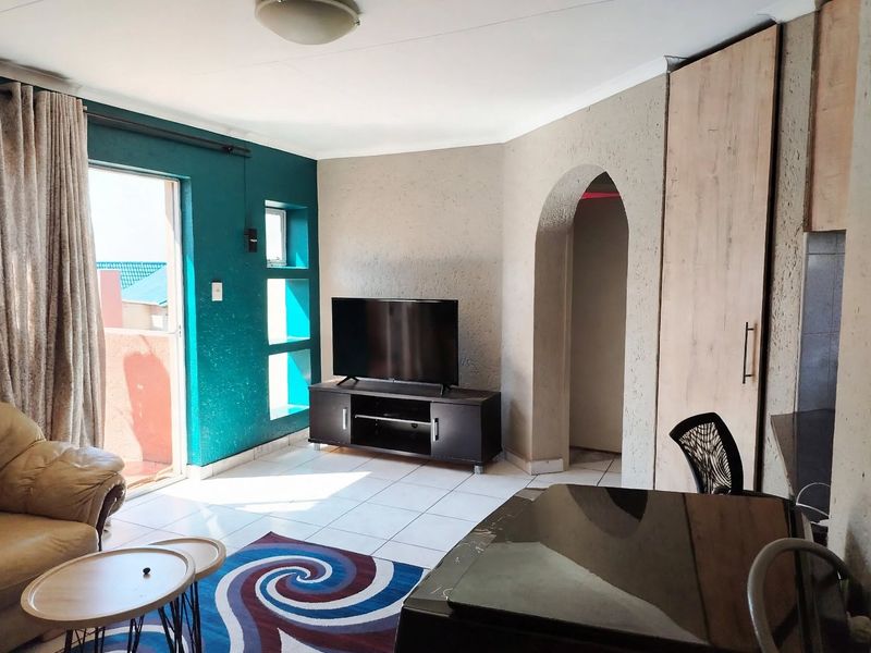 Open plan living area featuring tiled floors, a distinctive archway, and direct access to an outdoor balcony through a sliding glass door.