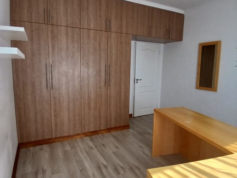 A bedroom featuring extensive built-in wooden cabinetry, laminate flooring, and a built-in desk area with recessed ceiling lighting.