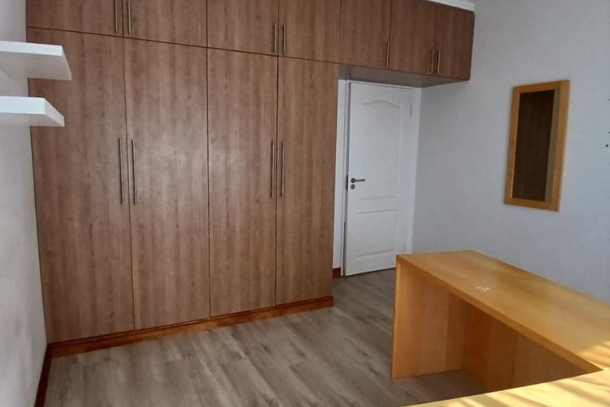 A bedroom featuring extensive built-in wooden cabinetry, laminate flooring, and a built-in desk area with recessed ceiling lighting.