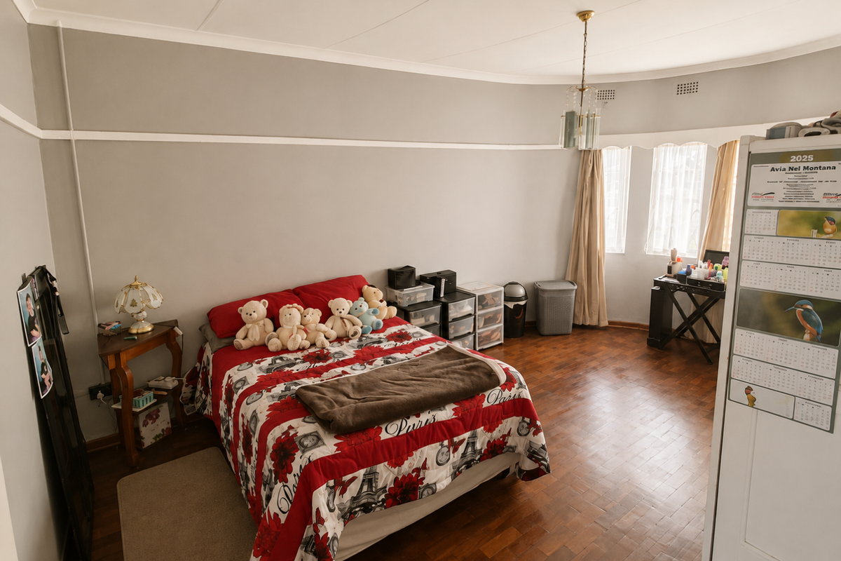 A spacious bedroom featuring warm parquet flooring, coved ceilings, and a central light fixture, offering a comfortable and well-maintained living space.