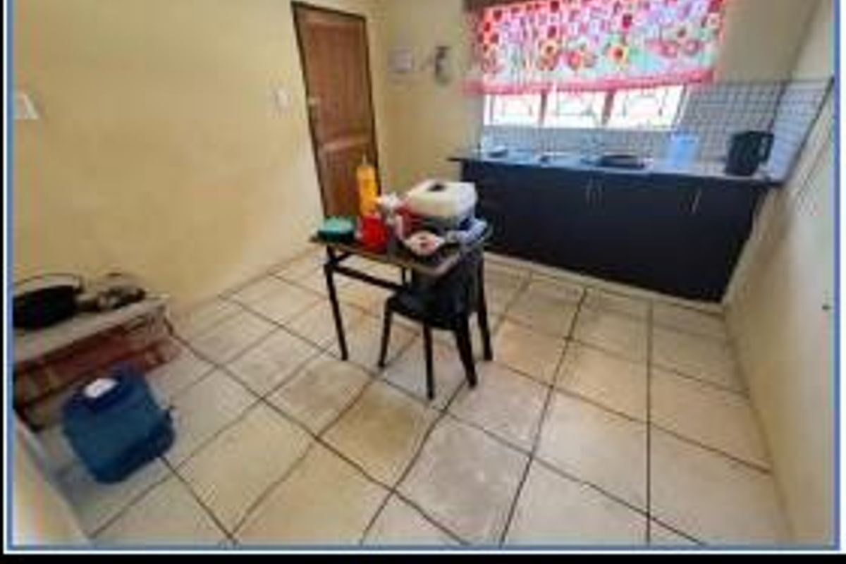 A functional kitchen featuring dark cabinetry, tiled flooring, and a window with natural light, offering a practical space for meal preparation.