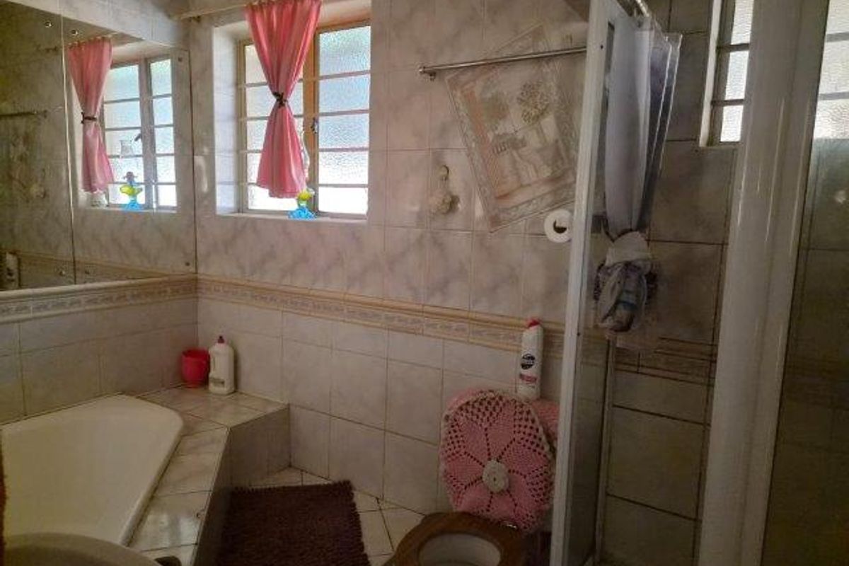 A dated bathroom featuring a built-in bathtub, a separate shower enclosure, and tiled wall finishes throughout.