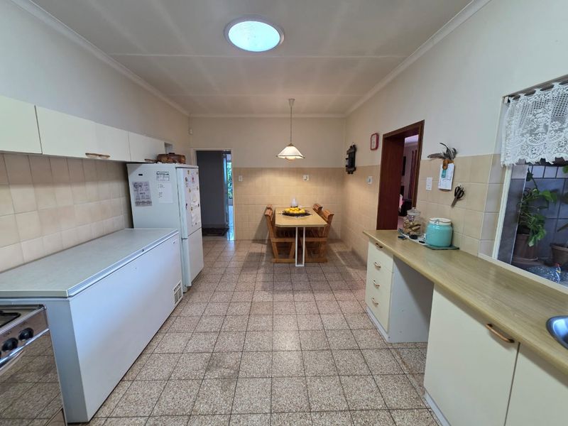 A functional kitchen featuring tiled flooring, ample built-in cabinetry, laminate countertops, and a skylight, with an integrated dining area.
