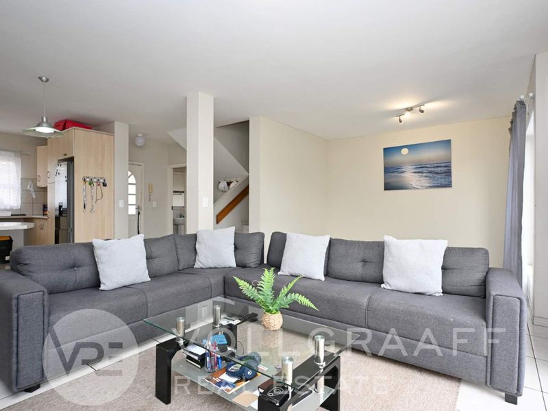 Open-plan living area featuring tiled flooring, a functional kitchen space, and a staircase leading to the upper level.