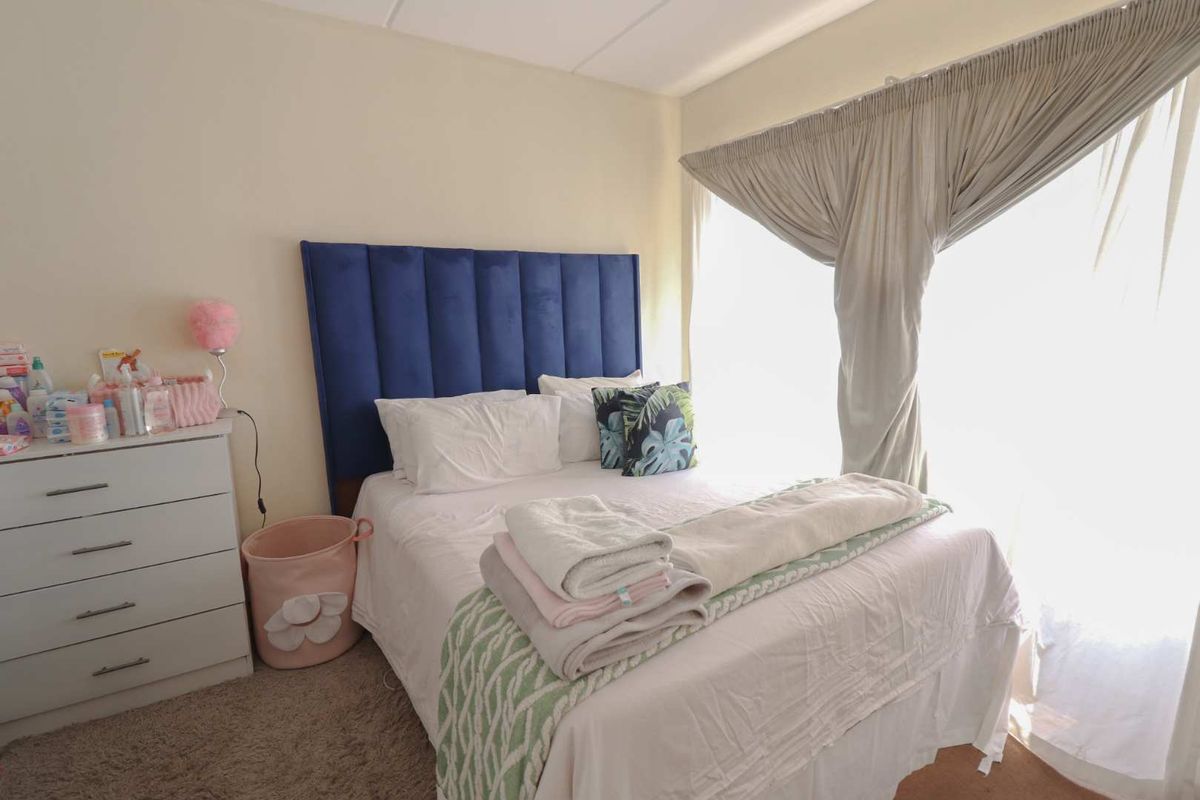 A bedroom featuring carpeted flooring and large windows with curtain tracks, providing natural light and a comfortable living space.