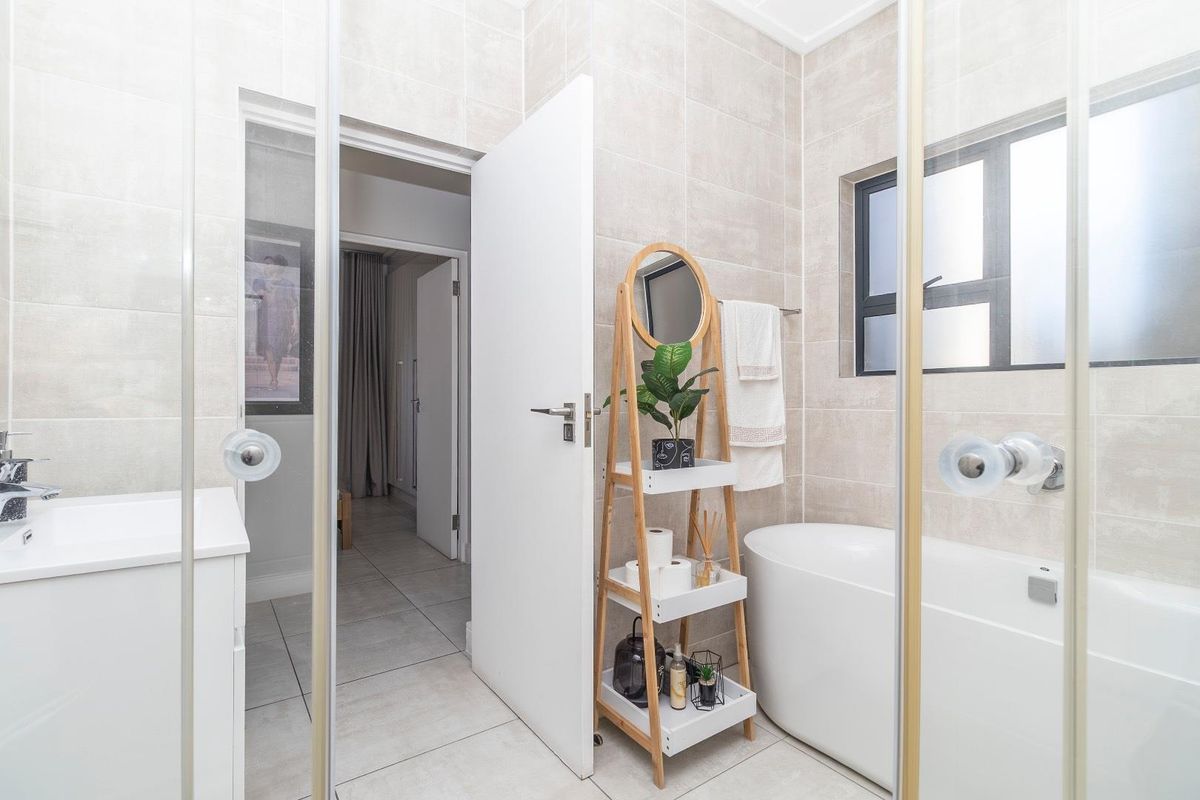 Modern bathroom featuring a freestanding bathtub, glass-enclosed shower, and neutral wall tiling, offering a clean and contemporary aesthetic.