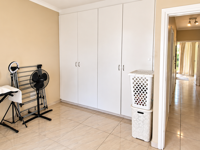 A spacious bedroom featuring neutral walls, large built-in cupboards, and tiled flooring, offering a clean and versatile space for customization.