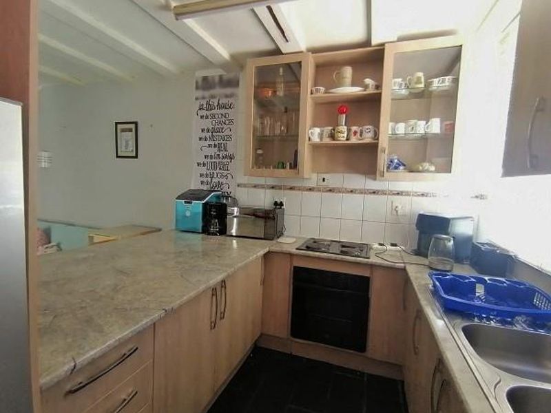 A functional kitchen featuring laminate countertops, built-in oven, electric hob, and ample cabinetry, offering a practical layout for daily meal preparation.