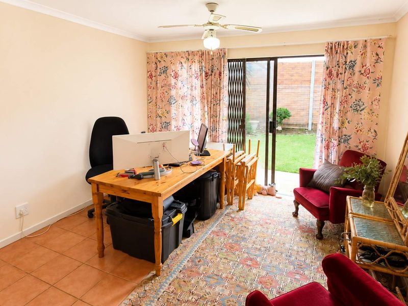 A living room featuring tiled flooring, a ceiling fan, and sliding glass doors providing direct access to the rear garden area.