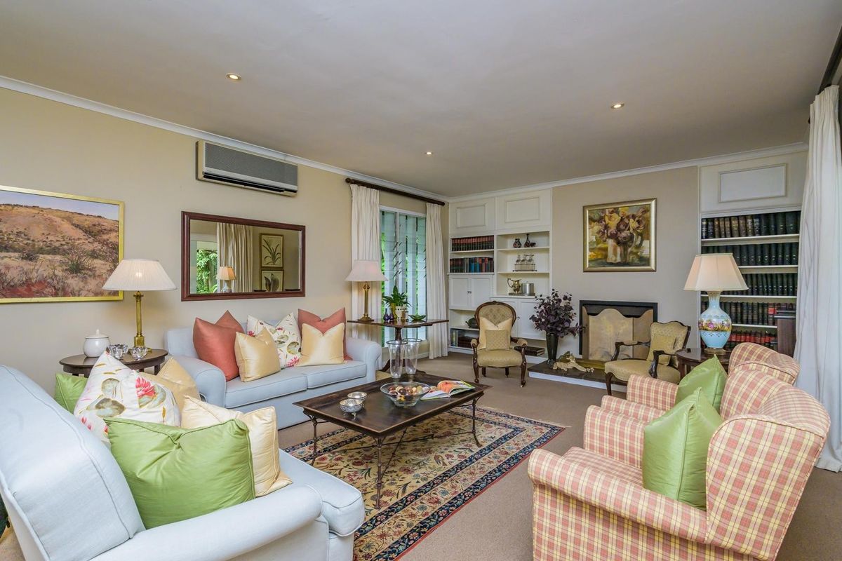 A comfortable living room featuring a fireplace, built-in library shelving, and a split-system air conditioner, with direct access to the garden.