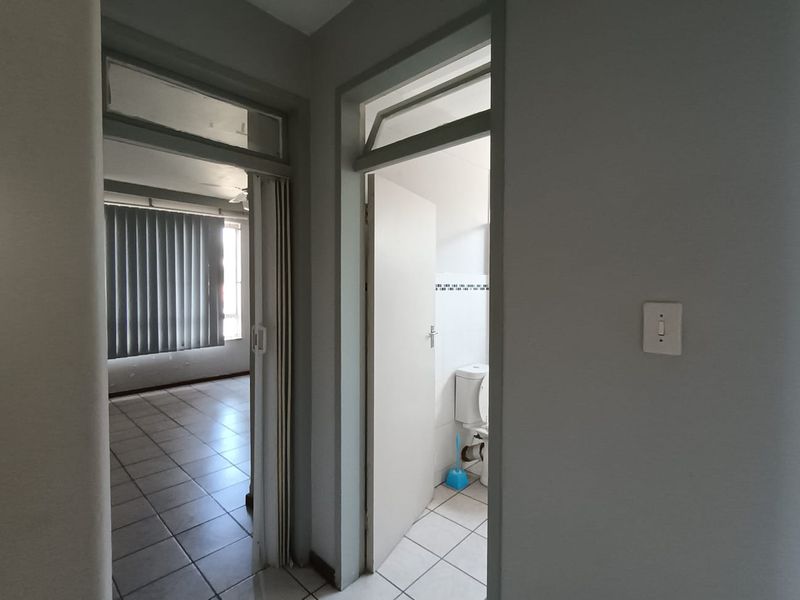 A functional hallway area featuring tiled flooring and access to adjacent rooms, including a bathroom with a visible toilet.