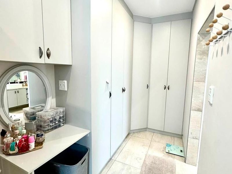 A well-maintained dressing area featuring extensive built-in cabinetry, a vanity counter, and modern tiled flooring.
