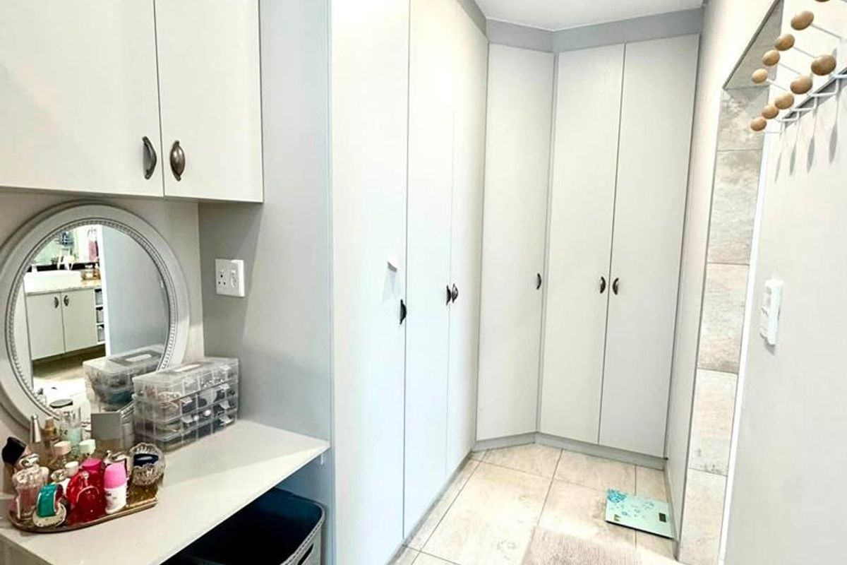A well-maintained dressing area featuring extensive built-in cabinetry, a vanity counter, and modern tiled flooring.