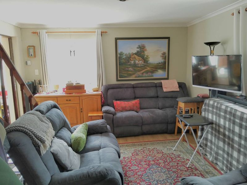 A comfortable living room featuring laminate flooring, coving, and an adjacent staircase, providing a functional and well-utilized space.