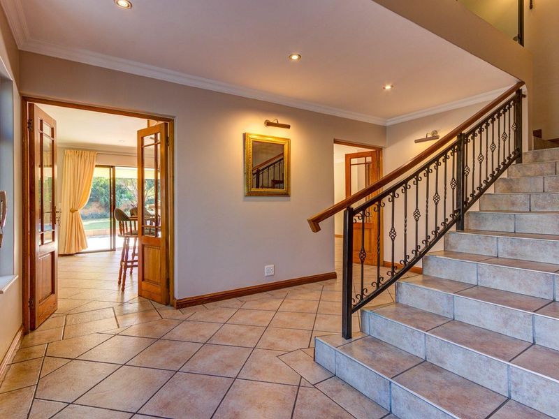 Spacious entrance hall featuring a tiled staircase with a decorative wrought iron balustrade, recessed lighting, and neutral finishes leading to adjacent living areas.