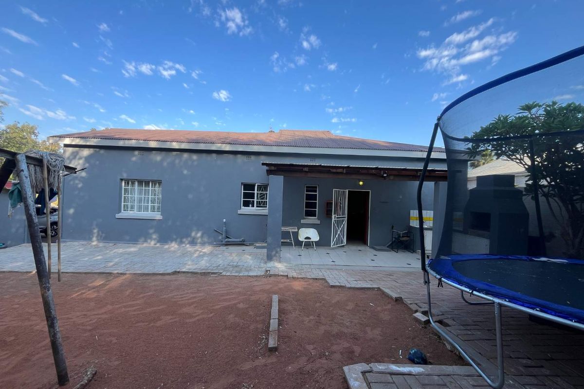 Rear view of the house featuring a covered patio area, paved outdoor space, and a built-in brick braai facility.