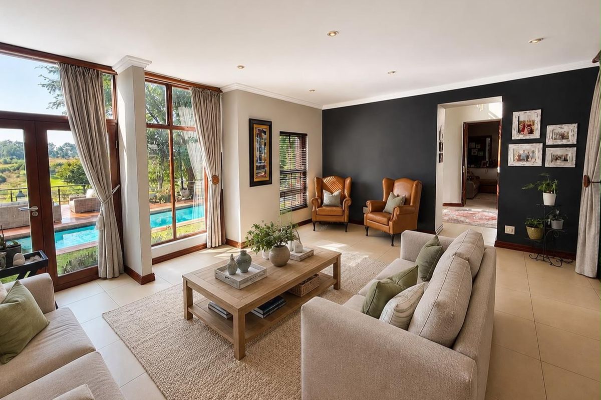A bright and spacious living room featuring large timber-framed windows, tiled flooring, and direct access to an outdoor patio and pool area.