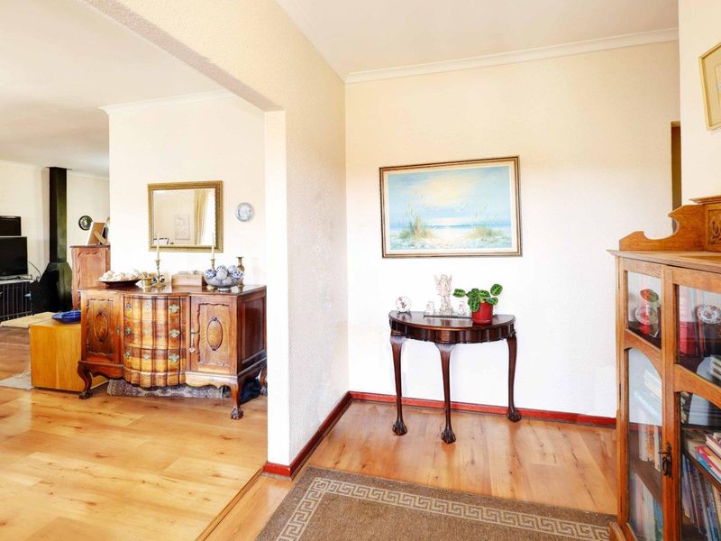 A bright living area featuring hardwood flooring, a classic archway transition, and a built-in wood-burning fireplace in the adjacent space.