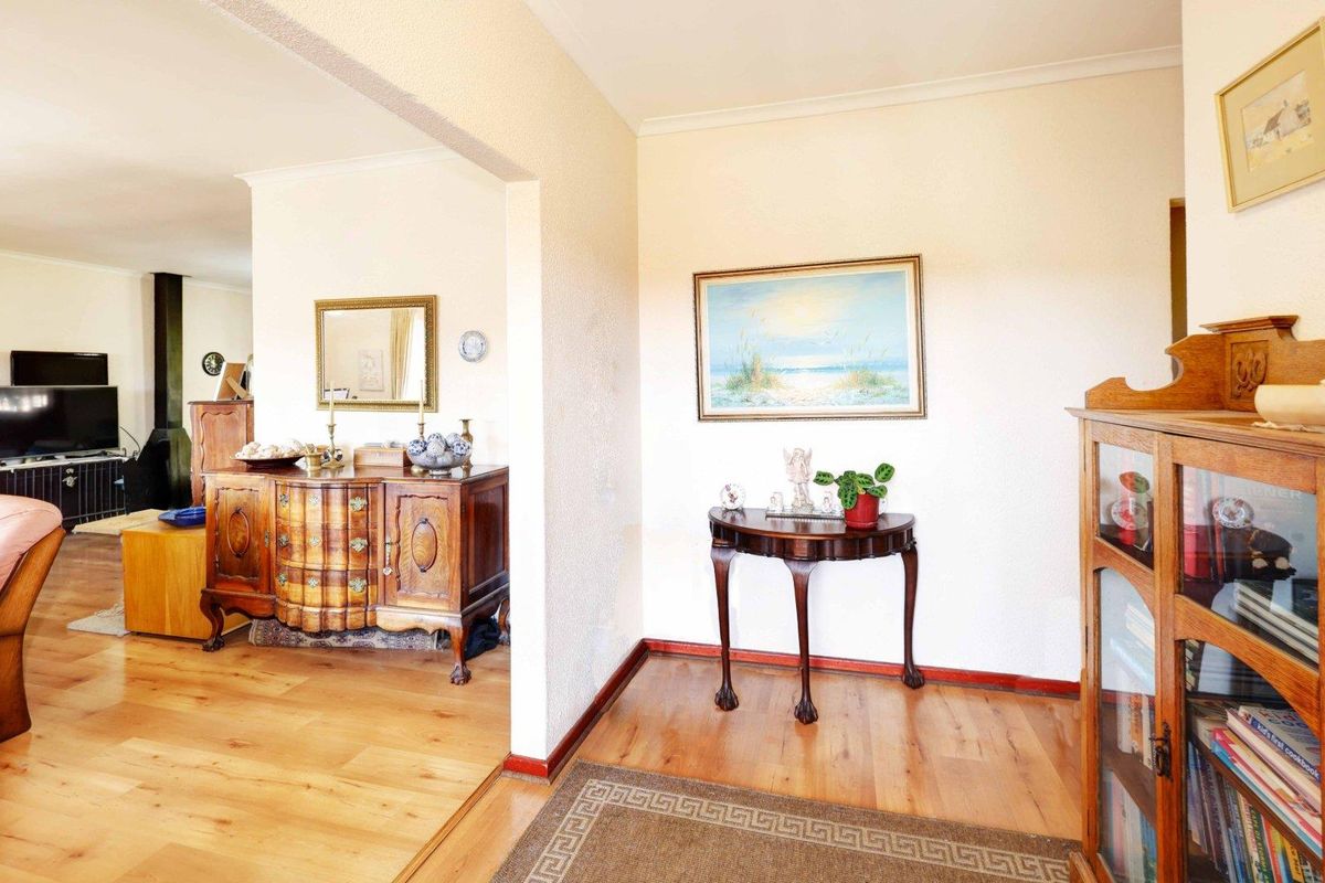 A bright living area featuring hardwood flooring, a classic archway transition, and a built-in wood-burning fireplace in the adjacent space.