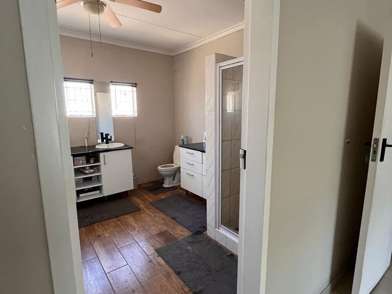 A functional bathroom featuring a vanity with basin, a separate shower enclosure, toilet, and wood-look tiled flooring.