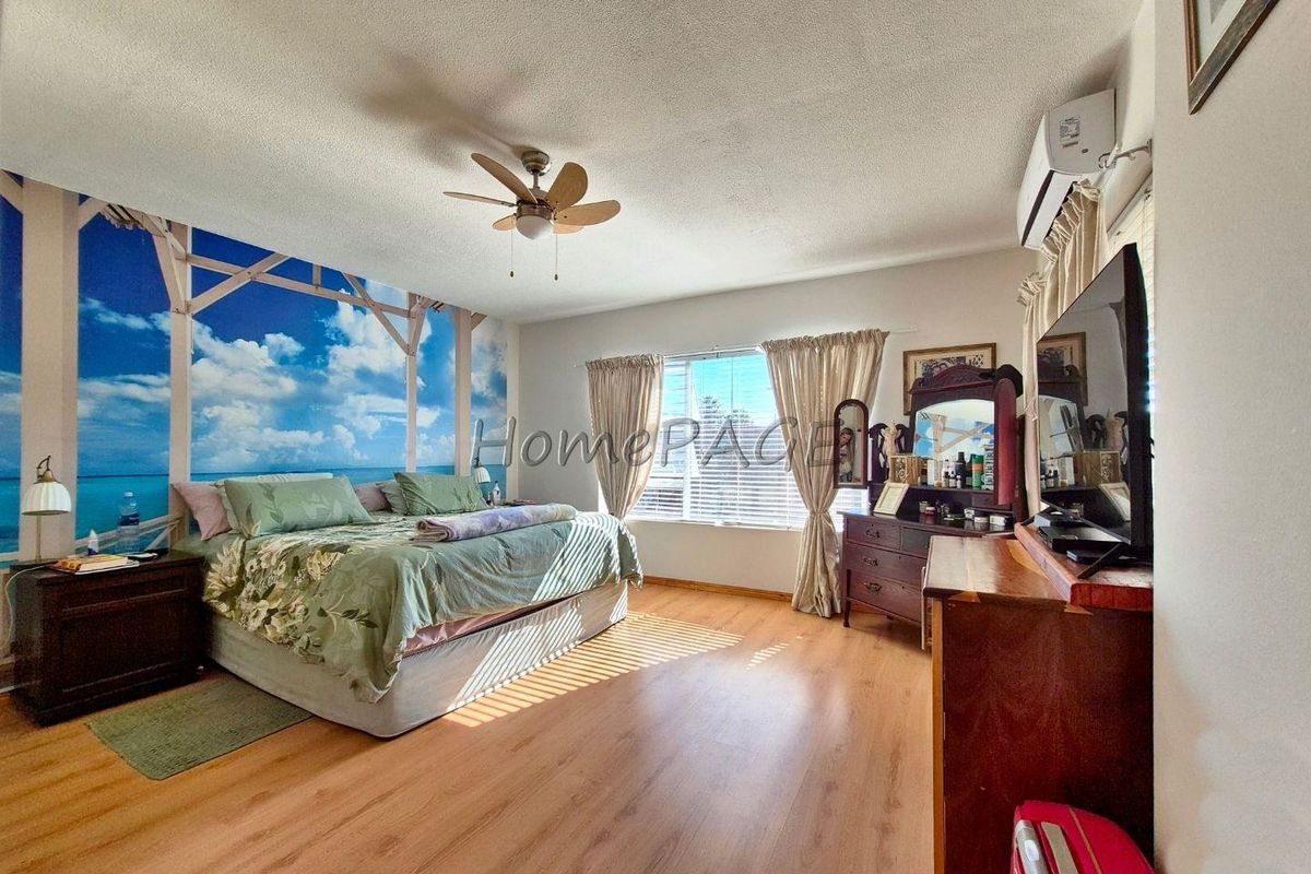 Spacious bedroom featuring wood-look laminate flooring, a ceiling fan, and a wall-mounted air conditioning unit.