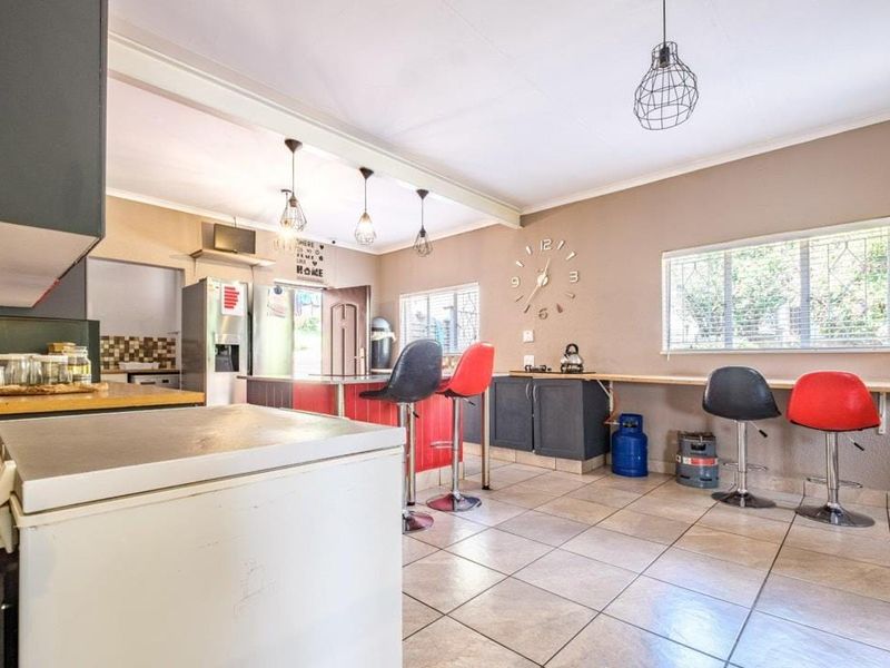 Spacious kitchen featuring a central island, built-in breakfast bar, tiled flooring, and ample cabinetry, offering a functional layout for cooking and casual dining.