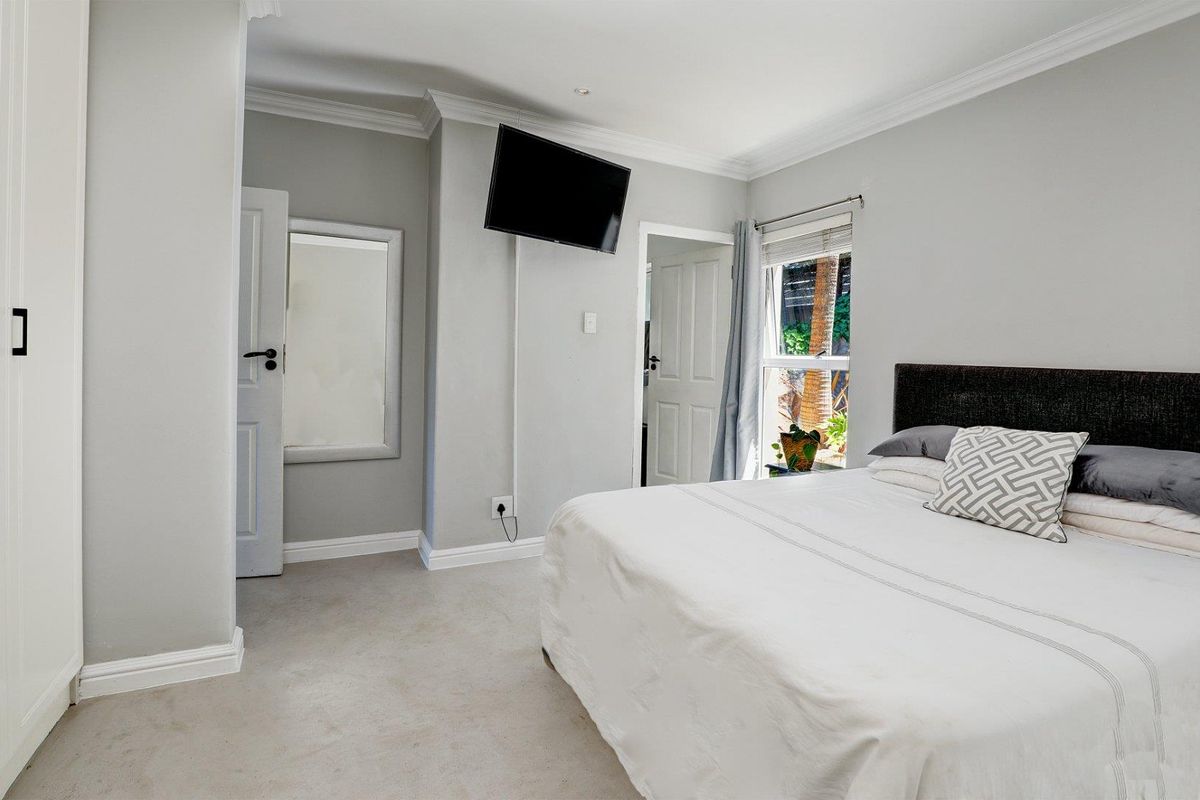 A well-maintained bedroom featuring neutral wall tones, crown molding, built-in cabinetry, and a window providing natural light.