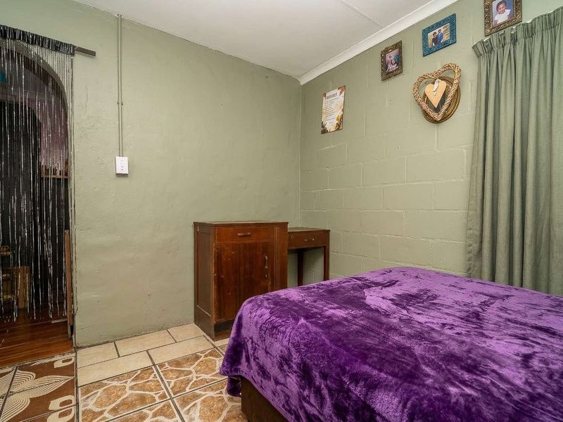 A bedroom featuring tiled flooring and painted blockwork walls with an arched entryway.