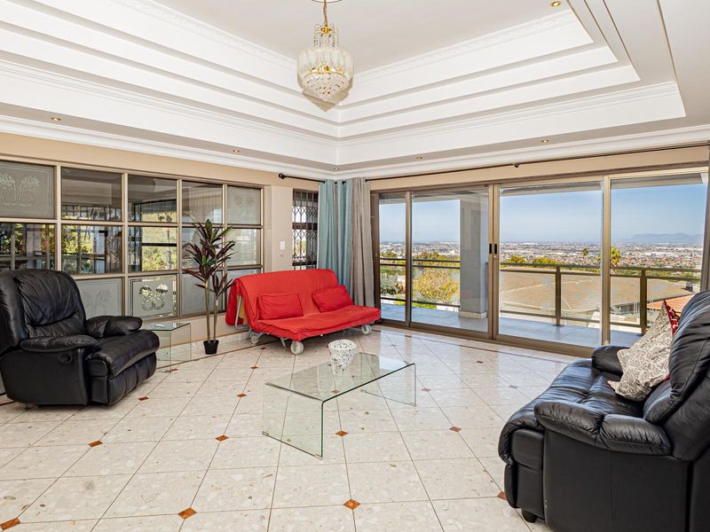 Spacious living room featuring a decorative tray ceiling, tiled flooring, and large sliding glass doors that open to a scenic balcony view.
