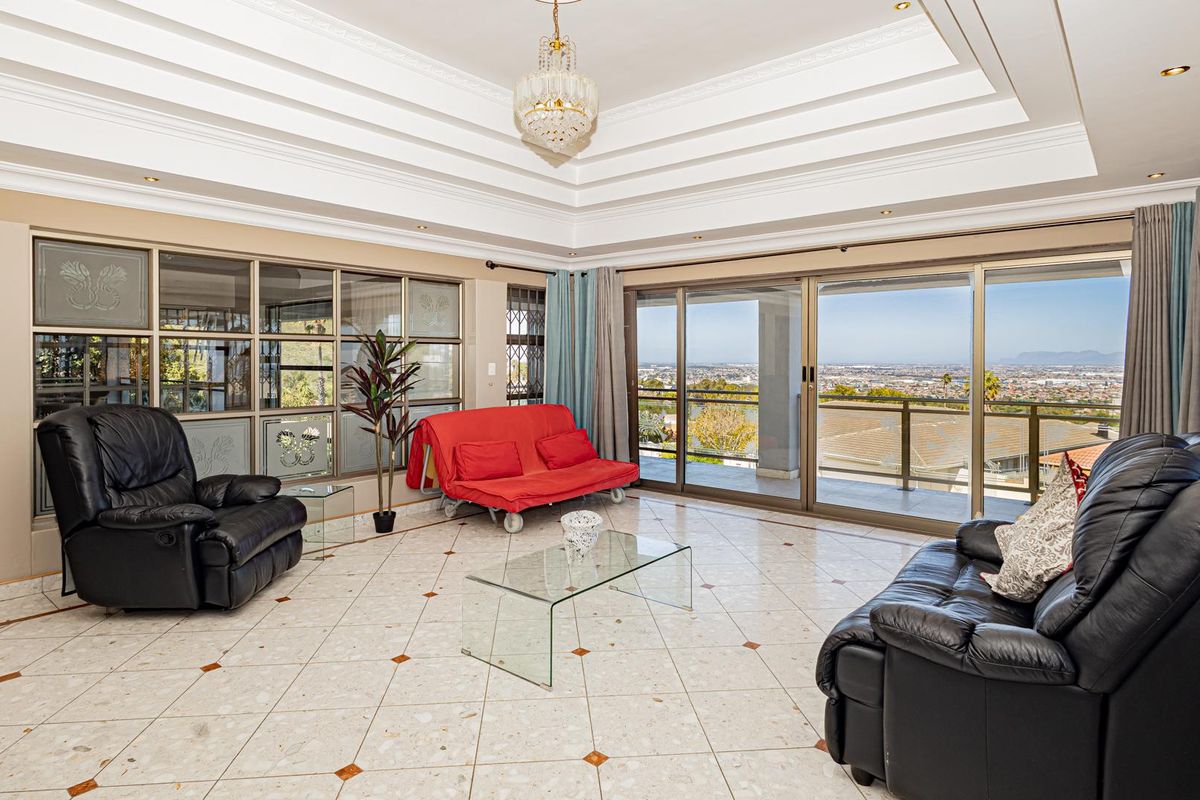 Spacious living room featuring a decorative tray ceiling, tiled flooring, and large sliding glass doors that open to a scenic balcony view.