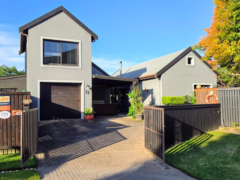 Front view of a modern house featuring a paved driveway, secure gated entrance, garage, and well-maintained exterior finishes.