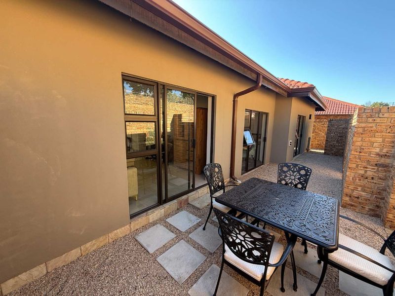 A private rear patio area featuring paved sections, gravel landscaping, and sliding glass door access to the interior living space.