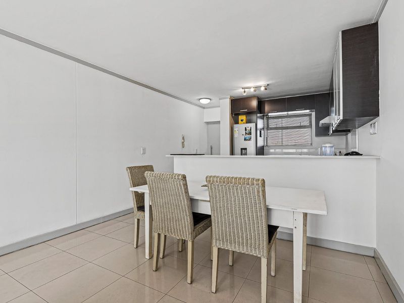 Open plan kitchen and dining area featuring tiled flooring, built-in cabinetry, and a breakfast bar counter.