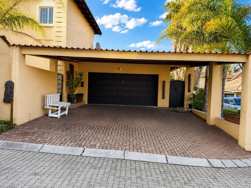 A well-maintained exterior view featuring a covered carport, paved driveway, and a secure sectional garage door.