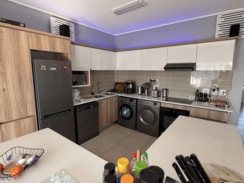 Modern kitchen featuring sleek cabinetry, stone countertops, integrated appliances, and a functional layout with a central island.