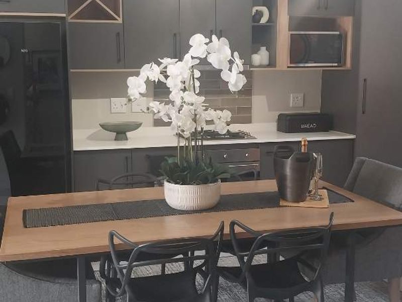 Modern open-plan kitchen and dining area featuring contemporary dark cabinetry, stone countertops, and integrated appliances.