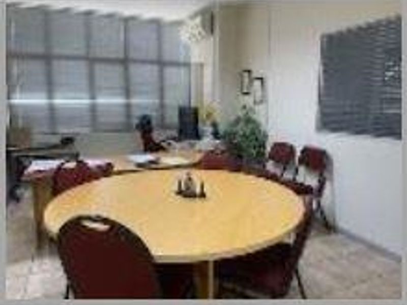 A functional office space featuring tiled flooring, large windows with venetian blinds, and a wall-mounted air conditioning unit.