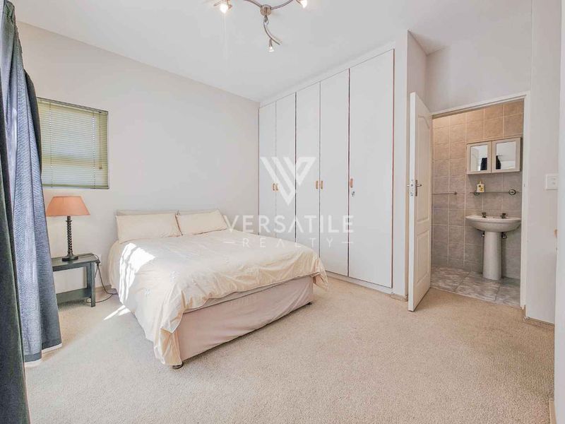 A bedroom featuring built-in cupboards and an en-suite bathroom with a pedestal sink.
