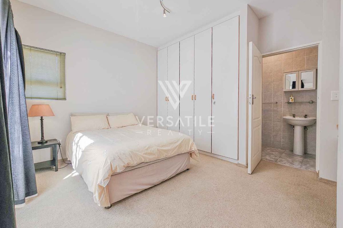 A bedroom featuring built-in cupboards and an en-suite bathroom with a pedestal sink.