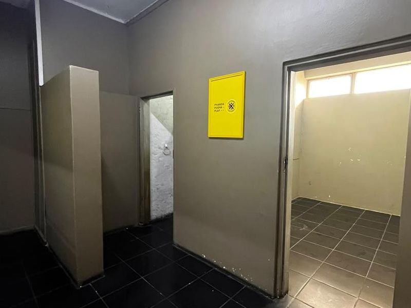 Interior view of a commercial hallway featuring dark tiled flooring and multiple doorways leading to separate utility or office spaces.