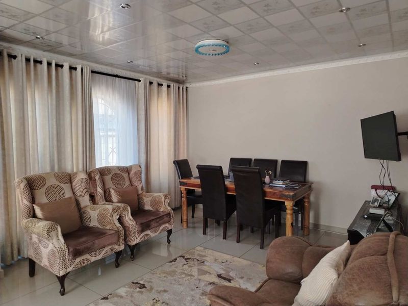 An open-plan living and dining area featuring tiled flooring and a suspended ceiling with integrated lighting.