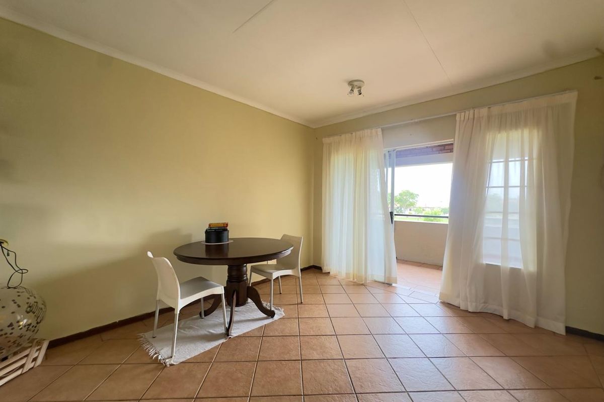 A living area featuring tiled flooring and sliding glass doors that open onto a private balcony, providing natural light and outdoor access.