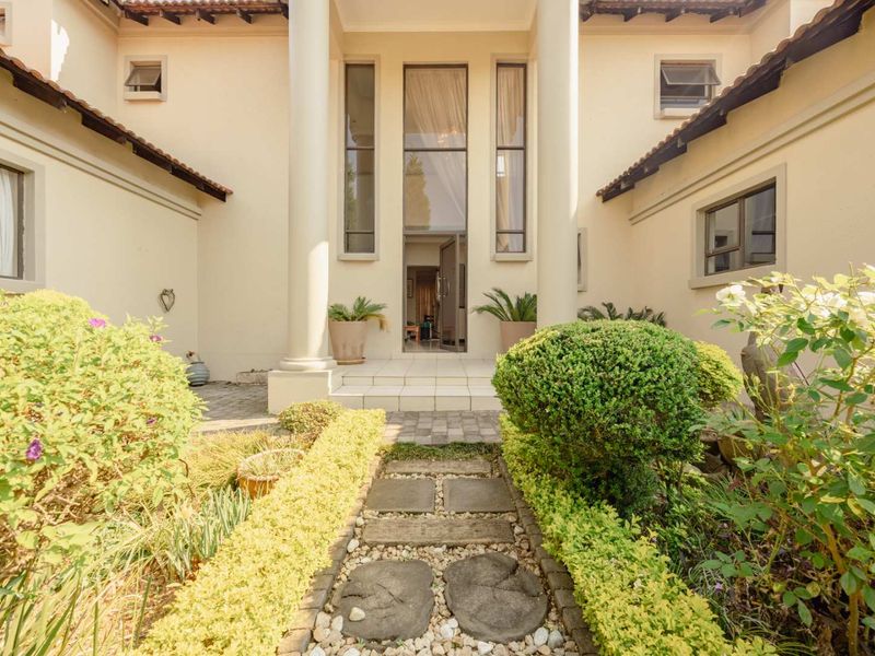 A grand front entrance featuring a stone pathway leading to a covered porch with prominent columns and tall windows.