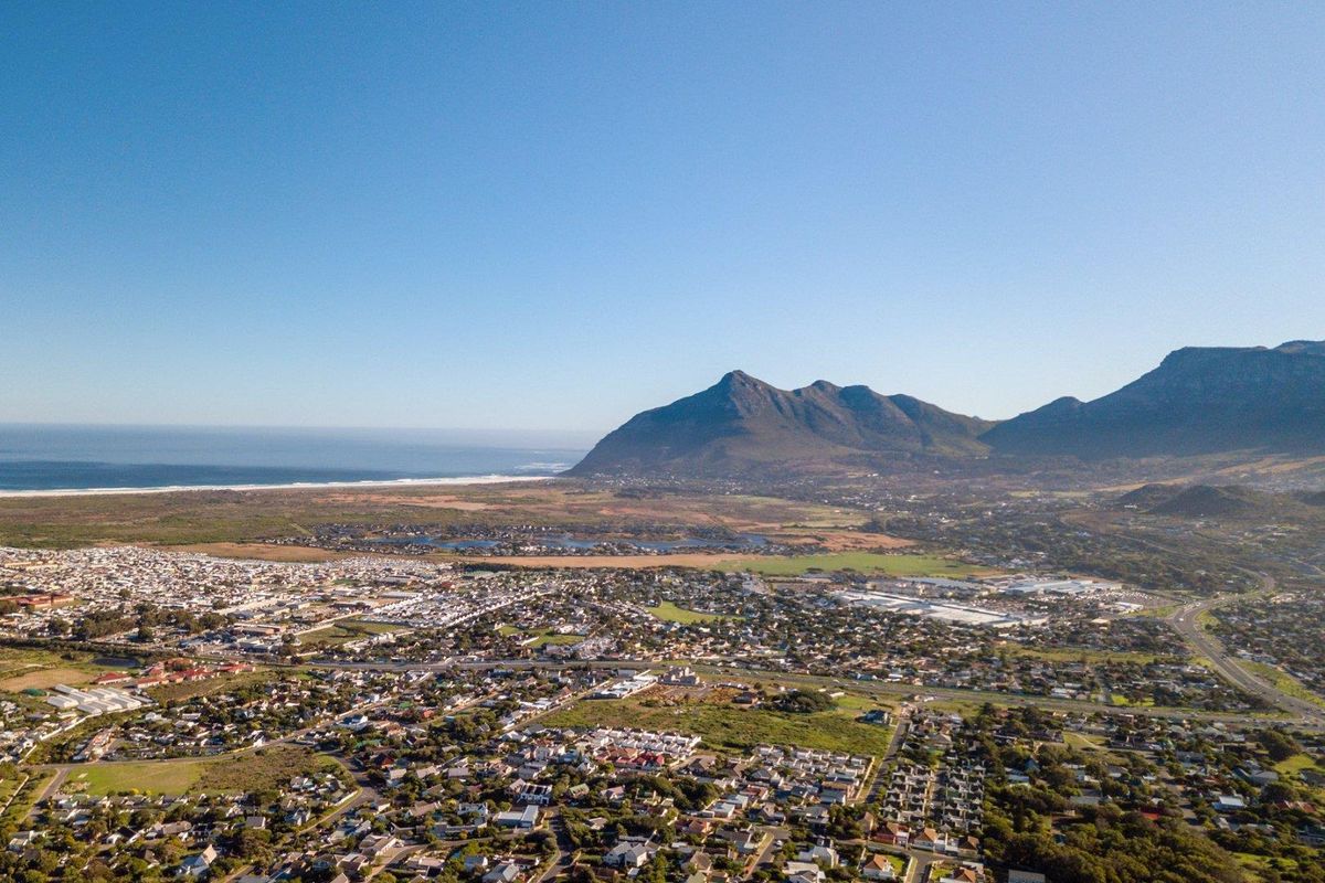 An expansive aerial view showcasing the surrounding residential neighborhood, coastal landscape, and prominent mountain range in the distance.
