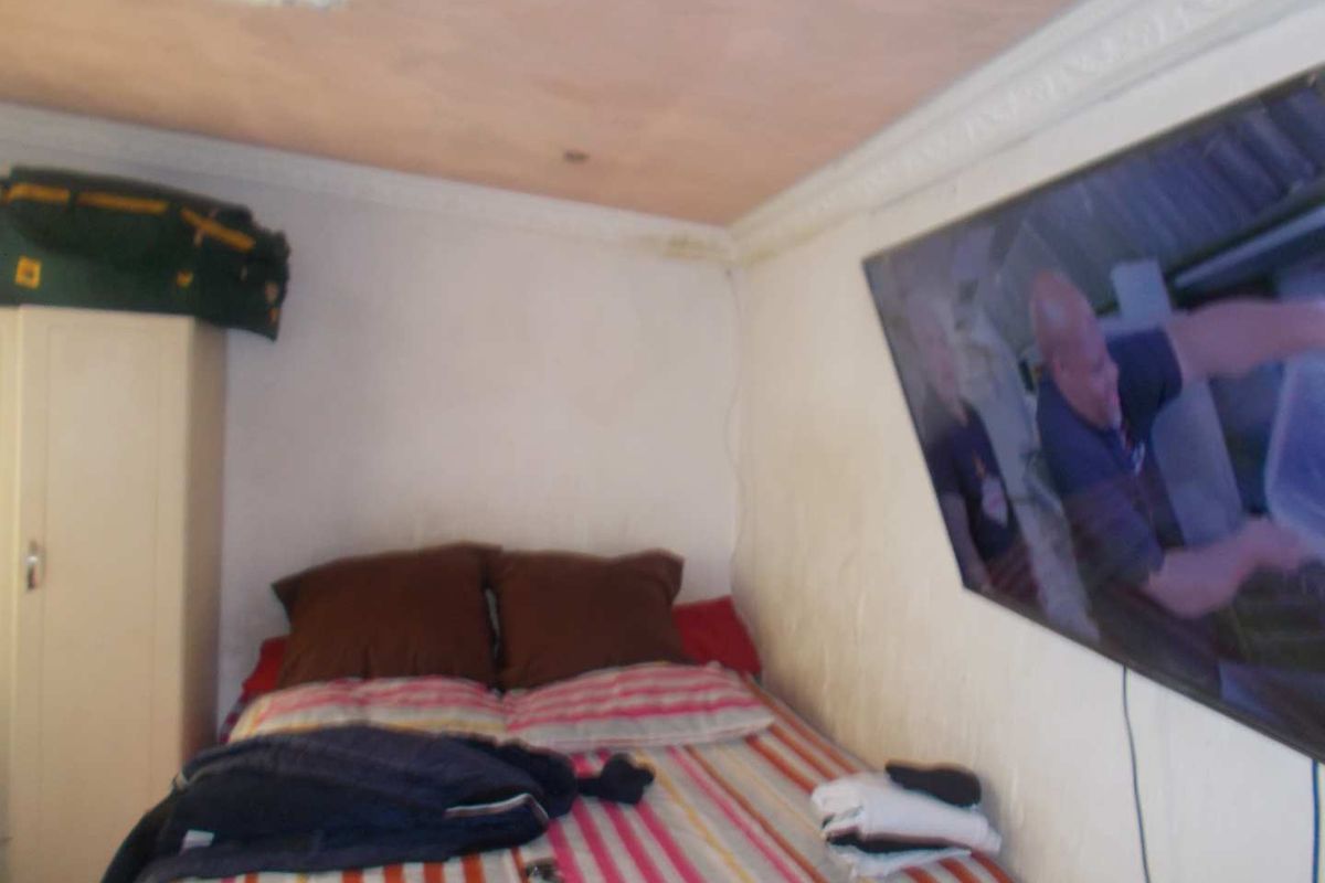 A compact bedroom featuring decorative ceiling cornicing and a wall-mounted television.