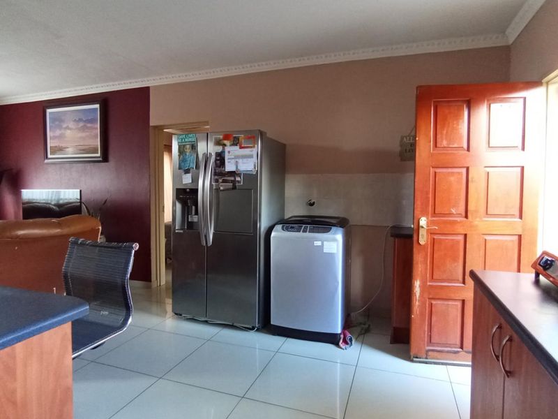 Open plan living and kitchen area featuring tiled flooring, built-in cabinetry, and direct access to an exterior door.